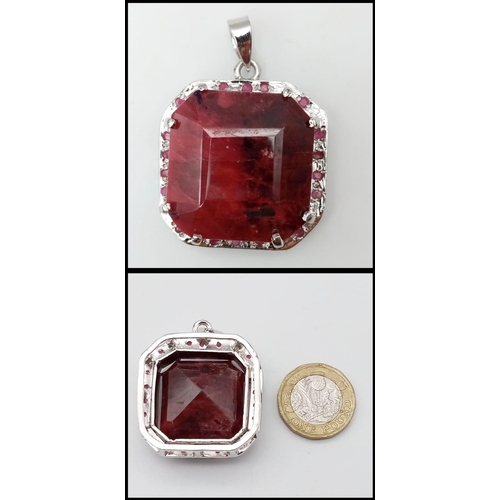 317 - An Octagon-Cut 128ct Ruby and 925 Silver Pendant. Large central stone with ruby surround. 4.5cm. 43.... 