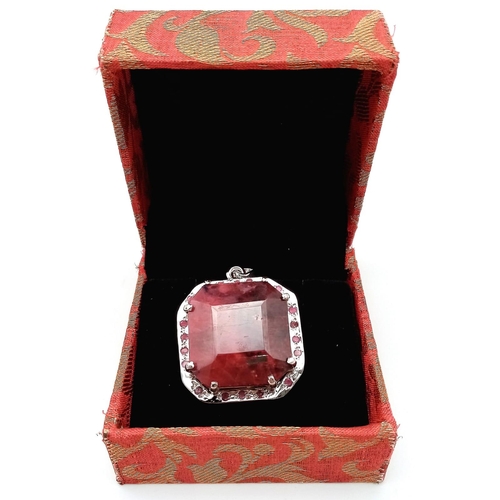 317 - An Octagon-Cut 128ct Ruby and 925 Silver Pendant. Large central stone with ruby surround. 4.5cm. 43.... 