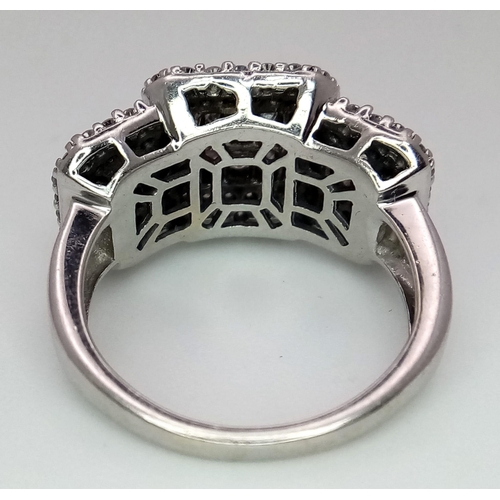 739 - An Art Deco Style 18K White Gold and Diamond Ring. A belt-buckle design of round and princess cut di... 