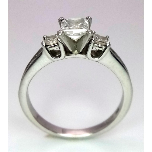 505 - A DESIGNER PLATINUM AND DIAMOND RING WITH SQUARE CENTRAL DIAMOND AND HAVING DIAMONDS TO EACH SHOULDE... 