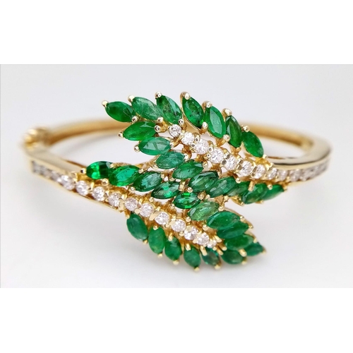 10 - A DIAMOND AND EMERALD LEAF DESIGN BANGLE IN CROSSOVER STYLE SET IN18K GOLD .    33.5gms     10457