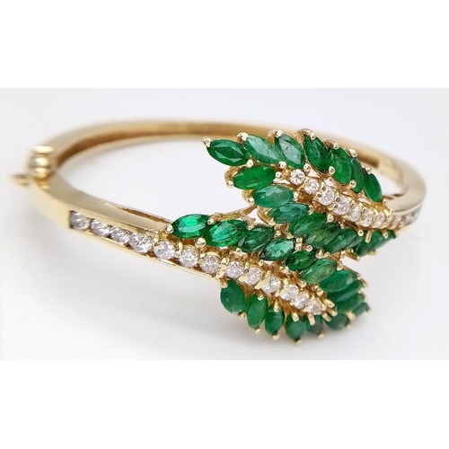 10 - A DIAMOND AND EMERALD LEAF DESIGN BANGLE IN CROSSOVER STYLE SET IN18K GOLD .    33.5gms     10457