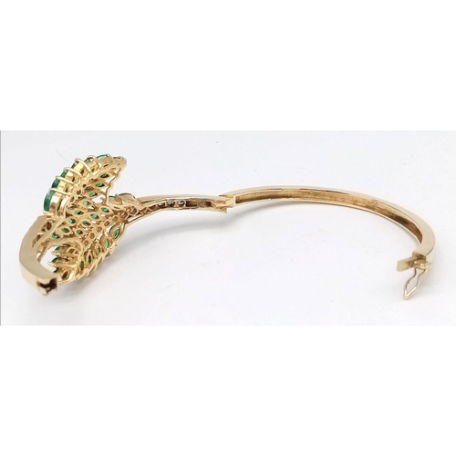 10 - A DIAMOND AND EMERALD LEAF DESIGN BANGLE IN CROSSOVER STYLE SET IN18K GOLD .    33.5gms     10457