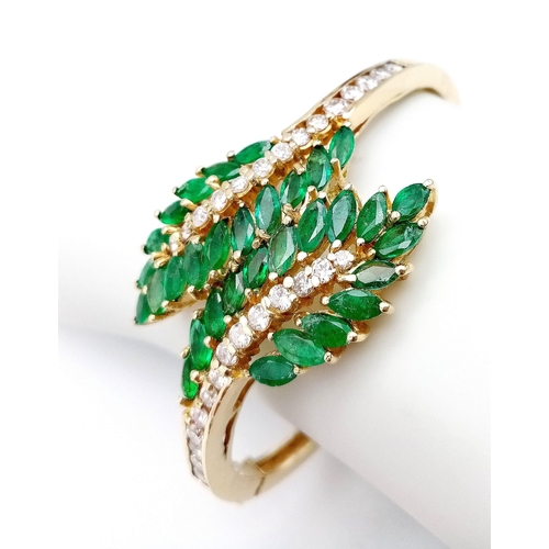 10 - A DIAMOND AND EMERALD LEAF DESIGN BANGLE IN CROSSOVER STYLE SET IN18K GOLD .    33.5gms     10457