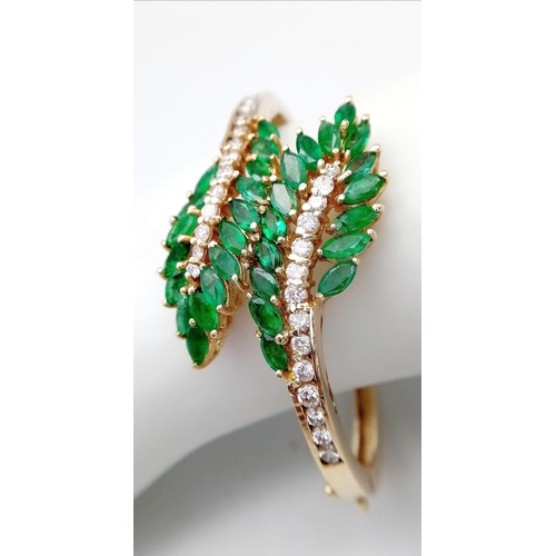 10 - A DIAMOND AND EMERALD LEAF DESIGN BANGLE IN CROSSOVER STYLE SET IN18K GOLD .    33.5gms     10457