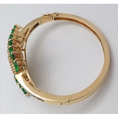 10 - A DIAMOND AND EMERALD LEAF DESIGN BANGLE IN CROSSOVER STYLE SET IN18K GOLD .    33.5gms     10457