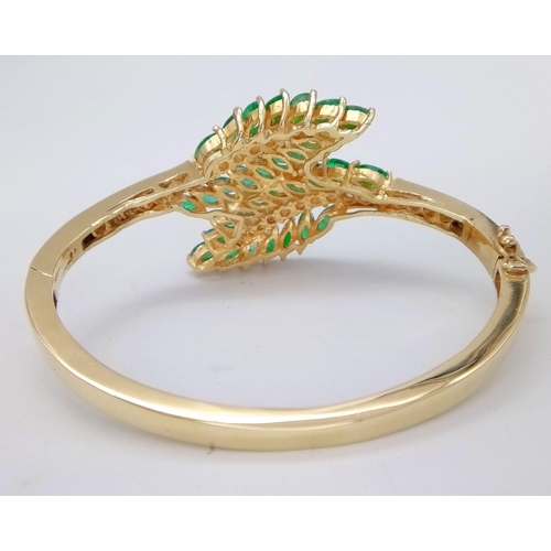 10 - A DIAMOND AND EMERALD LEAF DESIGN BANGLE IN CROSSOVER STYLE SET IN18K GOLD .    33.5gms     10457