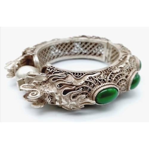 160 - A Chinese, antique, wonderfully crafted, silver, double-headed dragon bangle with green jade cabocho... 