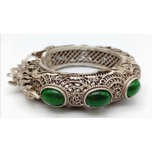 160 - A Chinese, antique, wonderfully crafted, silver, double-headed dragon bangle with green jade cabocho... 