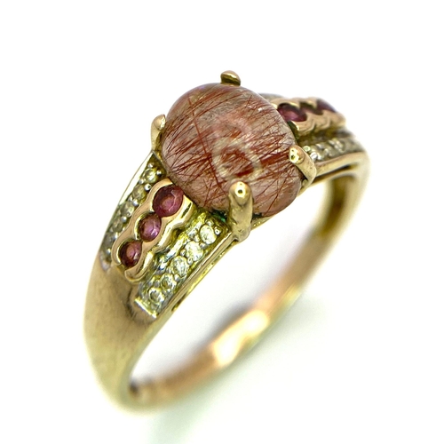 356 - A 9K Yellow Gold Rutilated Quartz, Diamond and Ruby Ring. Size V. 3.68g total weight. Central caboch... 