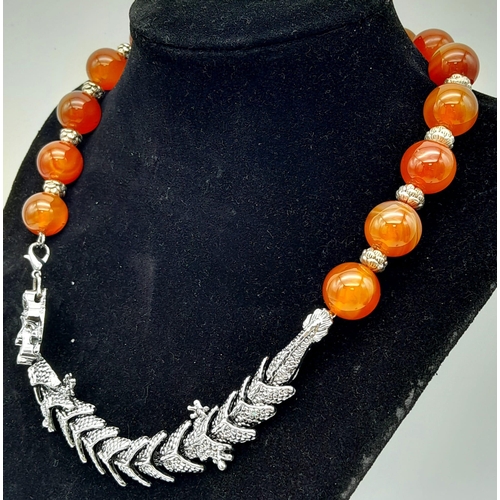 125 - An unusual, Oriental, carnelian necklace with a white metal (untested) large Chinese dragon clasp, a... 