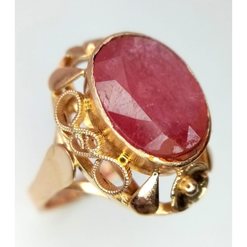 353 - A Vintage 18K Yellow Gold Ruby Ring. Central faceted oval ruby (5ct) in a raised decorative scroll f... 