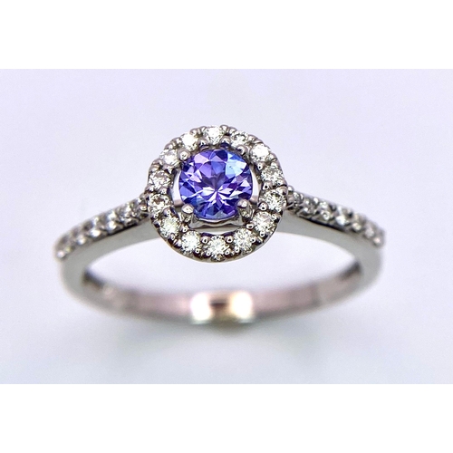 249 - An 18K White Gold Tanzanite and Diamond Ring. Central round cut tanzanite with diamond halo and shou... 