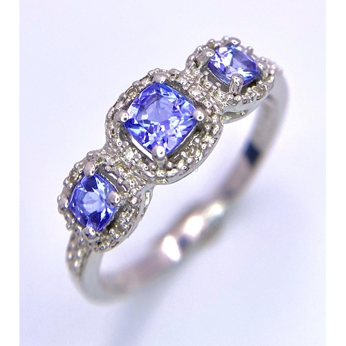 263 - A 9K White Gold Tanzanite and Diamond Ring. Three tanzanite stones with diamond surrounds. Size O. 2... 