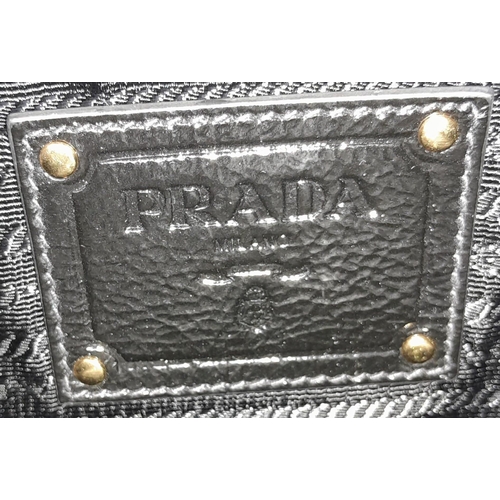 293 - A Prada Black Jewel Clutch. Textile exterior embellished with black stones. Gold toned hardware and ... 