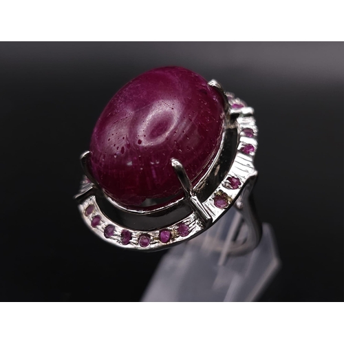 318 - A Ruby Gemstone and 925 Silver Ring. Oval cut central cabochon with ruby halo. Size O. 19g total wei... 