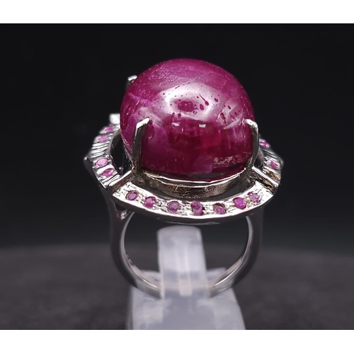 318 - A Ruby Gemstone and 925 Silver Ring. Oval cut central cabochon with ruby halo. Size O. 19g total wei... 