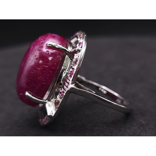 318 - A Ruby Gemstone and 925 Silver Ring. Oval cut central cabochon with ruby halo. Size O. 19g total wei... 