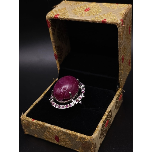 318 - A Ruby Gemstone and 925 Silver Ring. Oval cut central cabochon with ruby halo. Size O. 19g total wei... 