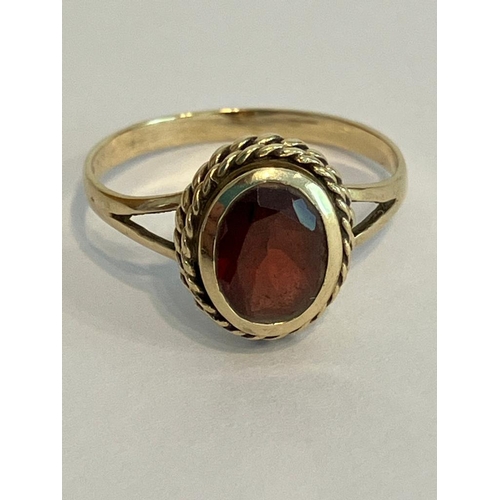 140 - Classic 9 carat GOLD RING with faceted oval Garnet set to top. Attractive twisted double rope mount.... 