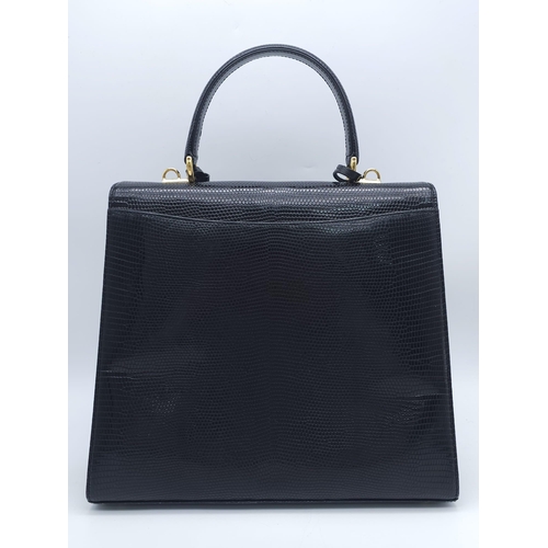 213 - Black Gucci Top Handle Bag.
Exotic, shiny lizard leather featuring gold toned hardware, flip-lock cl... 