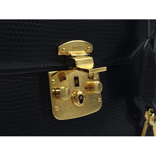 213 - Black Gucci Top Handle Bag.
Exotic, shiny lizard leather featuring gold toned hardware, flip-lock cl... 