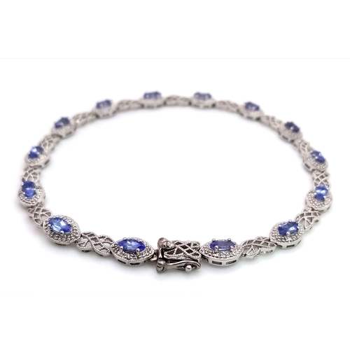 31 - A 9K White Gold, Purple Sapphire and Diamond Tennis Bracelet. Eye-shaped links with sapphire centres... 