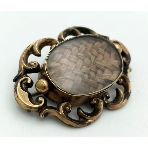 311 - An Antique 9K Yellow Gold (tested) Memorial/Mourning Brooch. Hair encapsulation centre with a scroll... 