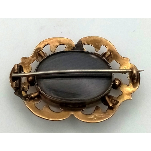 311 - An Antique 9K Yellow Gold (tested) Memorial/Mourning Brooch. Hair encapsulation centre with a scroll... 