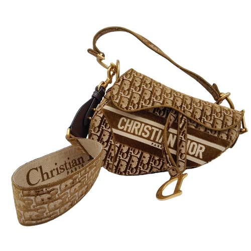 68 - Christian Dior Saddle Handbag.
Brown monogrammed velvet bag with gold tone hardware. Additional, rem... 