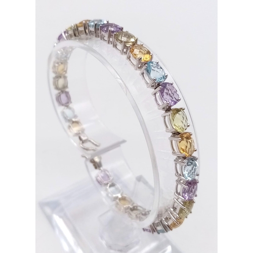 1234 - A 9K White Gold Multi-Gemstone Tennis Bracelet. Includes beautifully oval-cut faceted amethyst, topa... 