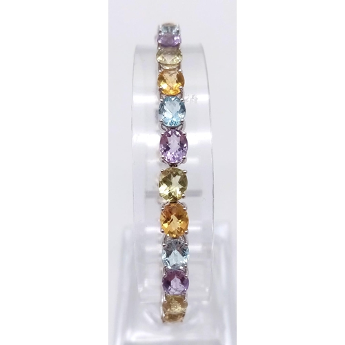 1234 - A 9K White Gold Multi-Gemstone Tennis Bracelet. Includes beautifully oval-cut faceted amethyst, topa... 