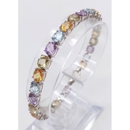 1234 - A 9K White Gold Multi-Gemstone Tennis Bracelet. Includes beautifully oval-cut faceted amethyst, topa... 