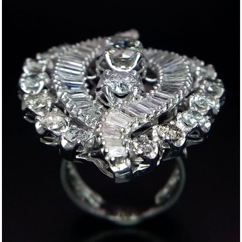 1261 - An 18K White Gold Diamond Dress Ring. This 'all seeing' diamond masterpiece begins with three centra... 