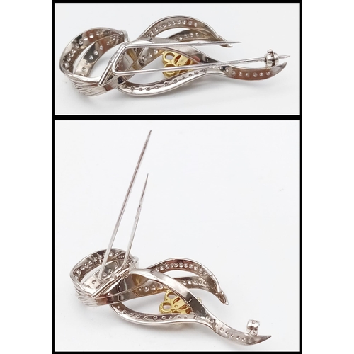 1554 - Diamond encrusted 18kt White & Yellow Gold Brooch.
Beautifully woven White Gold design, adorned with... 