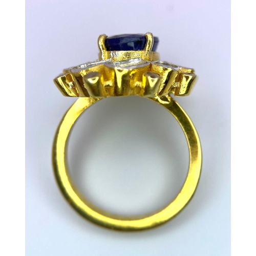 126 - An eye-catching silver and gold ring with an oval cut blue sapphire surrounded by a group of large n... 