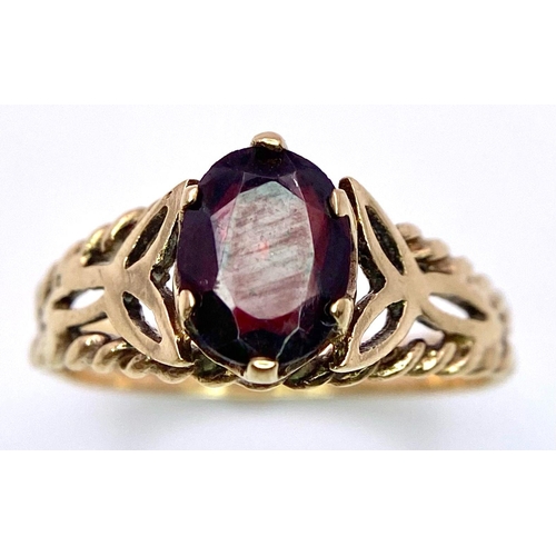 221 - A Vintage 9K Yellow Gold and Garnet Ring. Central oval garnet set within pierced decoration. Size P.... 