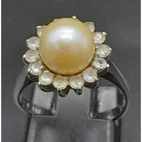 1761 - An 18K White Gold, Pearl and Diamond Ring. Central South Sea pearl with an old cut diamond halo. Siz... 