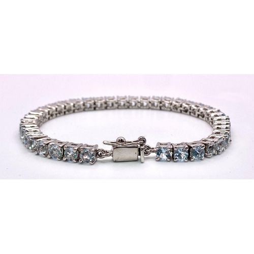 1303 - A Blue Topaz Tennis Bracelet. Round cut topaz gemstones set in 925 silver. 18cm length. 21.5g total ... 