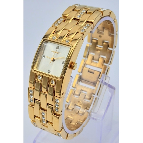 1387 - A Vintage Hamnett Ladies Watch. 
Gold Tone stainless steel with set crystals, unworn with protective... 