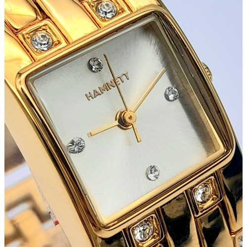 1387 - A Vintage Hamnett Ladies Watch. 
Gold Tone stainless steel with set crystals, unworn with protective... 