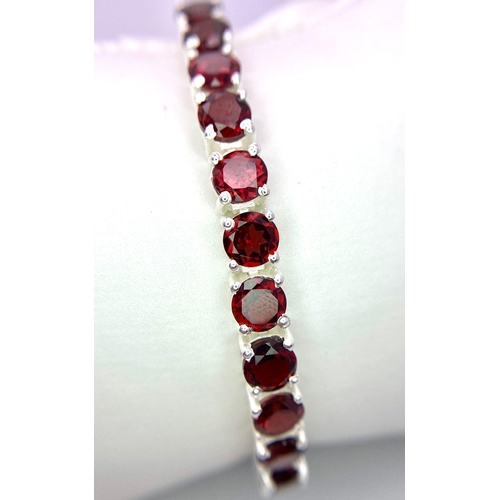 1422 - A Garnet Gemstone Tennis Bracelet set in 925 Silver. Round cut garnets. 18cm. 21.2g total weight. Re... 