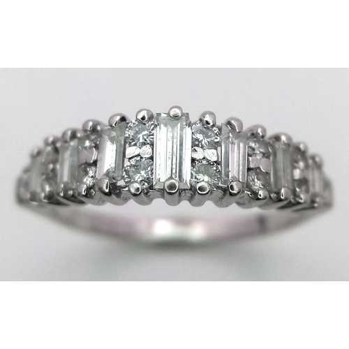 386 - A 9K White Gold Graduating Diamond Ring. Ever increasing baguette diamonds with round cut diamond ac... 