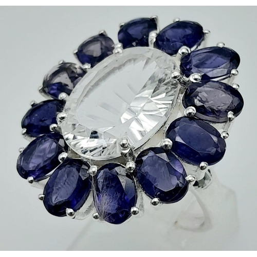 424 - A Blue Sapphire and White Topaz Gemstone Dress Ring. Central oval cut white topaz with a sapphire su... 