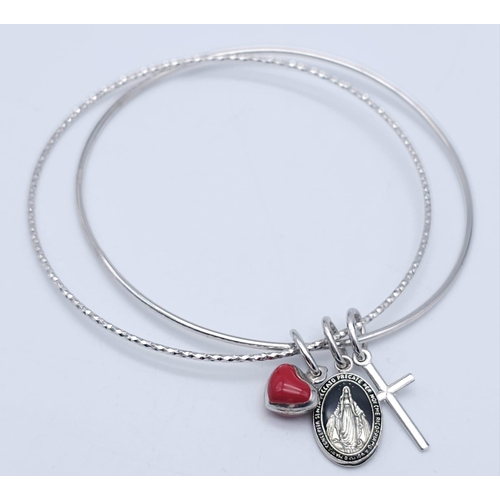 1334 - A STERLING SILVER CHARM BANGLE WITH RED HEART & CROSS. TOTAL WEIGHT 9.1G. DIAMETER 7CM. 3402