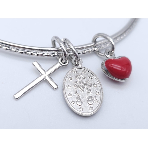 1334 - A STERLING SILVER CHARM BANGLE WITH RED HEART & CROSS. TOTAL WEIGHT 9.1G. DIAMETER 7CM. 3402