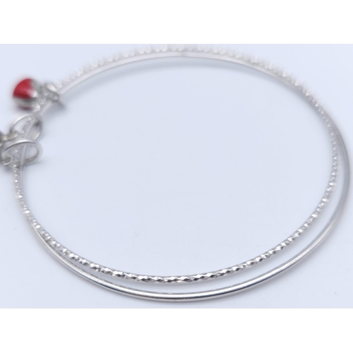 1334 - A STERLING SILVER CHARM BANGLE WITH RED HEART & CROSS. TOTAL WEIGHT 9.1G. DIAMETER 7CM. 3402