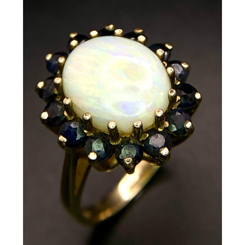 378 - A vintage, 9 K yellow gold ring with an Australian opal cabochon surrounded by numerous dark blue sa... 