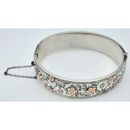 679 - A Sterling Silver Engraved Hinged Bangle with Safety Chain. 22.8g total weight.