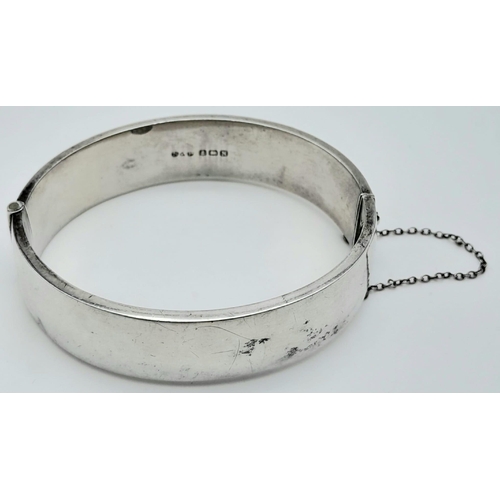 679 - A Sterling Silver Engraved Hinged Bangle with Safety Chain. 22.8g total weight.